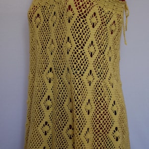May include: A yellow crochet dress with a delicate pattern. The dress has a halter neckline and a loose fit.