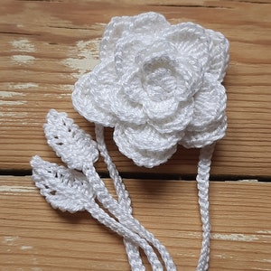 May include: White crocheted flower with leaves, a handmade embellishment for a craft project.