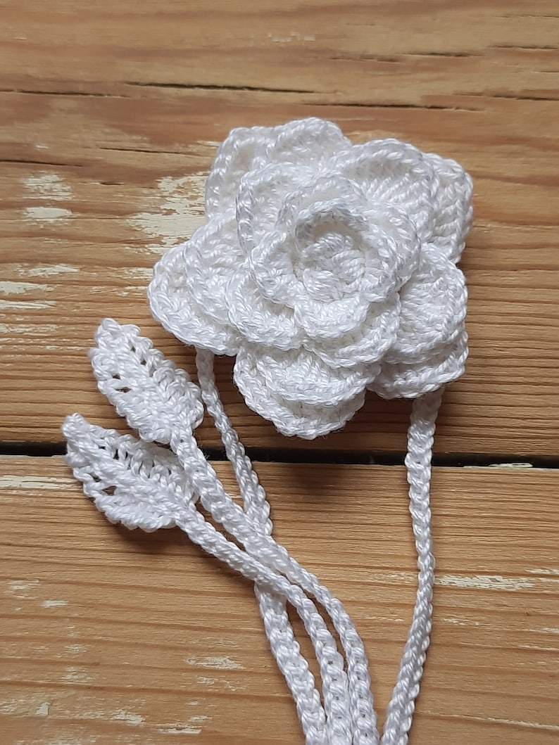 May include: White crocheted flower with leaves, a handmade embellishment for a craft project.