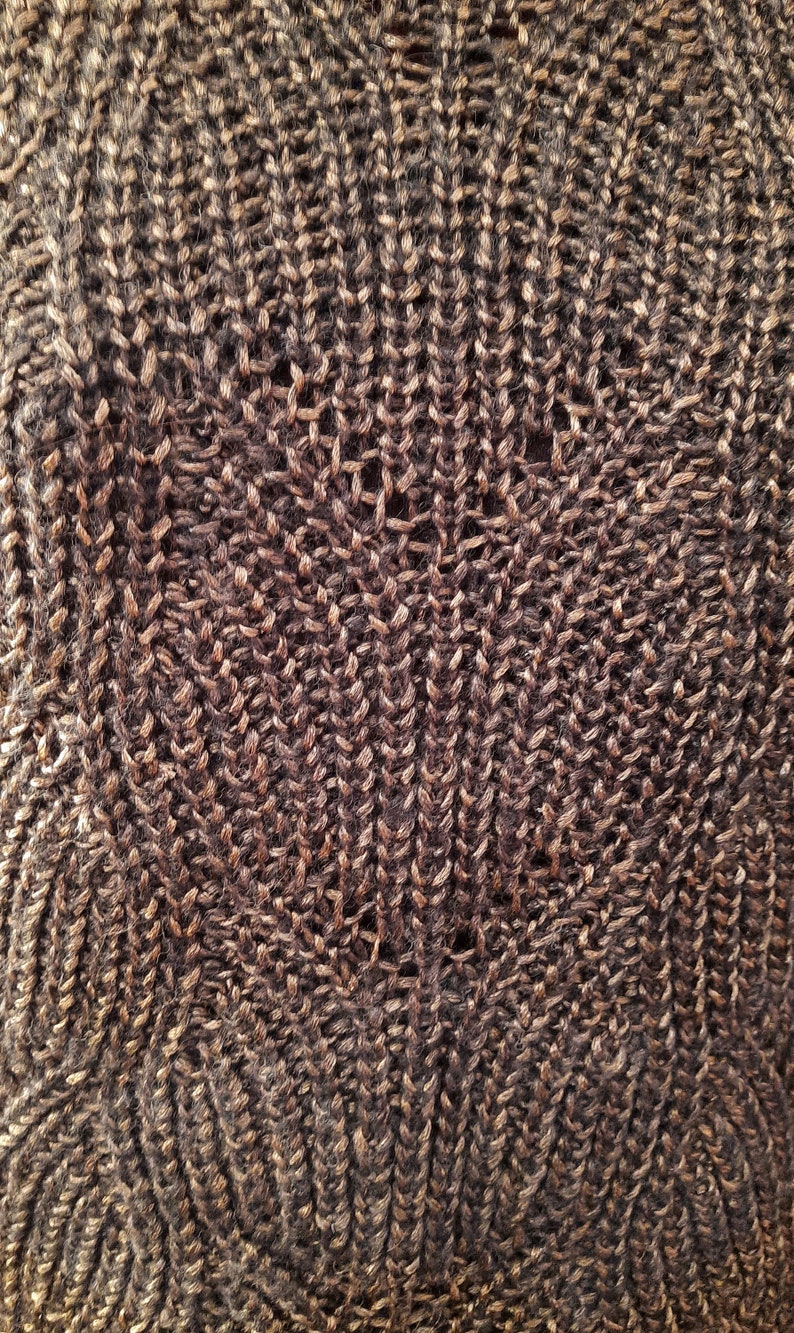 May include: Close-up of a brown knitted fabric with a textured pattern. The fabric has a subtle sheen and a soft, fuzzy texture.