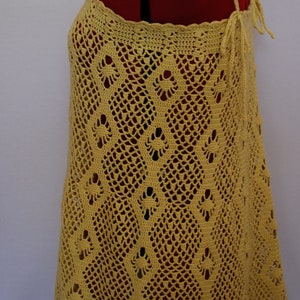 May include: A yellow crochet top with a delicate pattern. The top has a halter style with thin straps and a tie at the back.
