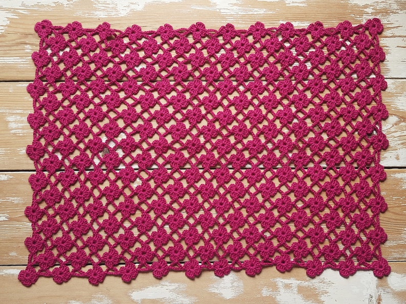 Puede incluir: Un encaje de ganchillo rosa con un patr&oacute;n floral. El encaje est&aacute; hecho con un hilo fino y tiene un aspecto delicado y de encaje.