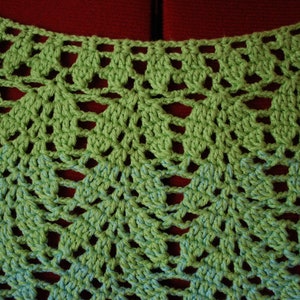 May include: Green crochet lace fabric with a delicate pattern. The fabric has a light green color and a darker green pattern.