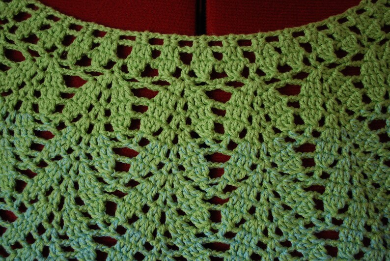 May include: Green crochet lace fabric with a delicate pattern. The fabric has a light green color and a darker green pattern.