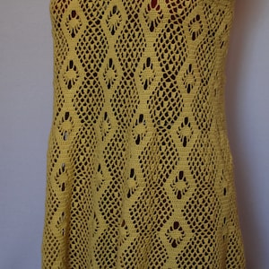 May include: A yellow crochet dress with a delicate, lacy pattern. The dress has a scoop neck and thin straps.