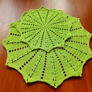 May include: Three green crocheted doilies with a starburst pattern. The doilies are layered on top of each other.