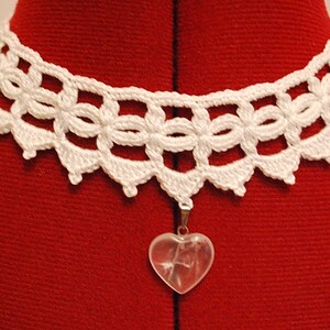 May include: White crocheted lace choker necklace with a clear heart-shaped crystal pendant.