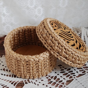 Pu&ograve; includere: Una scatola di immagazzinaggio rotonda in crochet con un coperchio. Il coperchio ha un design decorativo tagliato al laser. La scatola &egrave; realizzata in filato beige naturale.