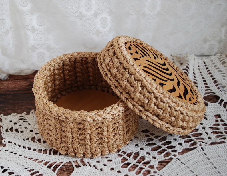 Pu&ograve; includere: Una scatola di immagazzinaggio rotonda in crochet con un coperchio. Il coperchio ha un design decorativo tagliato al laser. La scatola &egrave; realizzata in filato beige naturale.