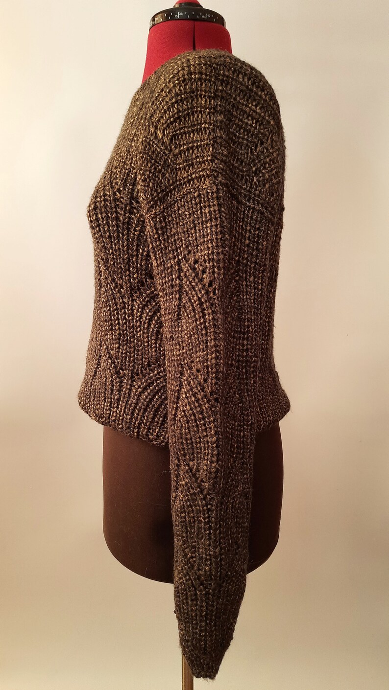 May include: A brown knitted sweater with a textured pattern. The sweater is on a dress form.