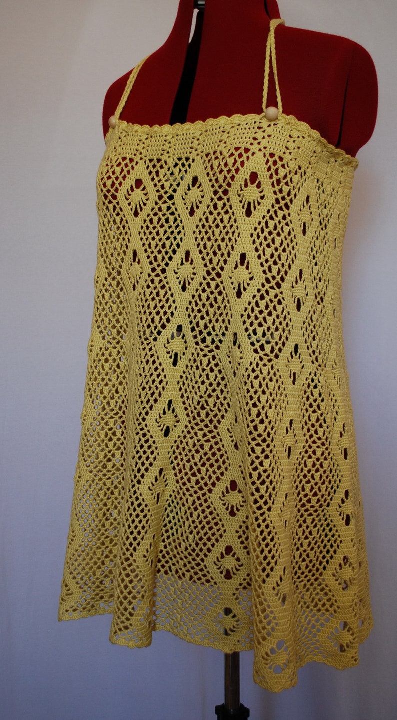 May include: A yellow crochet top with a delicate, lacy pattern. The top has thin straps and a loose, flowing fit.