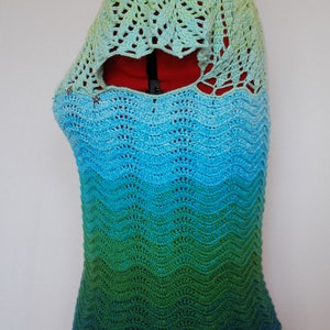 May include: A crocheted top with a green, blue, and light green ombre design. The top has a scalloped hem and a lacy neckline.