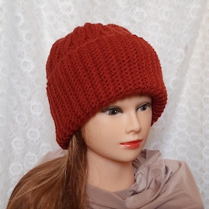 May include: A red knitted beanie hat with a ribbed texture. The hat is folded down at the brim.