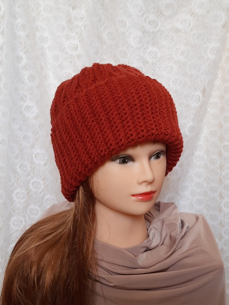 May include: A red knitted beanie hat with a ribbed texture. The hat is folded down at the brim.