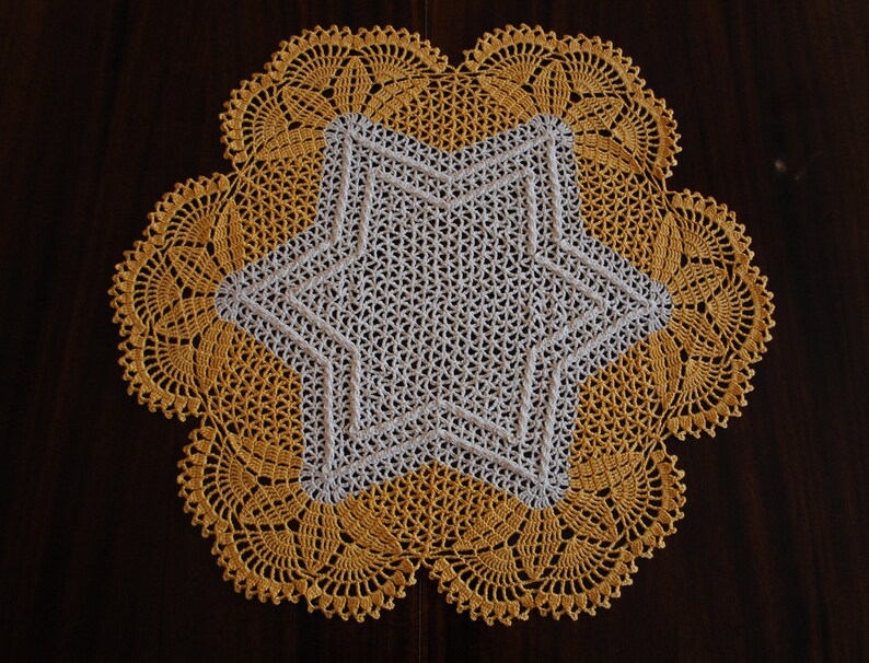May include: A crocheted doily with a white star in the centre and a yellow border.