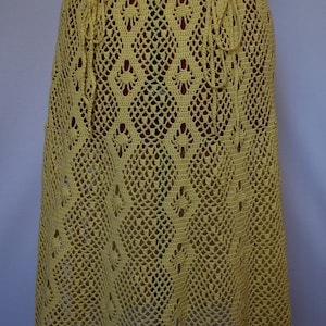 May include: A yellow crochet skirt with a delicate floral pattern. The skirt has a drawstring waist and a flowing, A-line silhouette.
