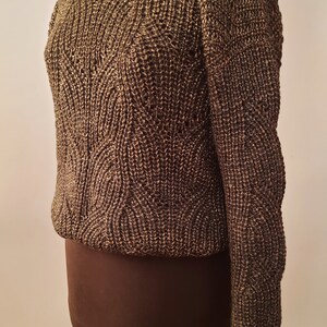 May include: A brown and gold knitted sweater with a textured pattern. The sweater is on a dress form.