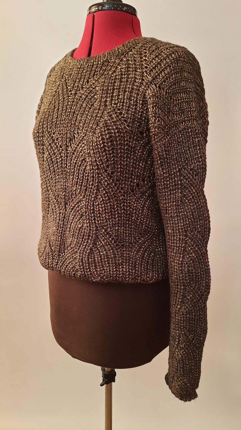 May include: A brown and gold knitted sweater with a textured pattern. The sweater is on a dress form.