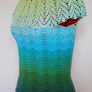 May include: A crocheted top with a green, blue, and turquoise ombre pattern. The top has a scalloped hem and a crocheted collar.