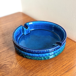 Op de afbeelding: Een ronde asbak van keramiek in blauw en groen met een getextureerd oppervlak.