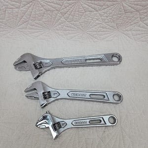 May include: Three silver adjustable wrenches with the word "KOBALT" printed on the handle. The wrenches are 6 inches, 8 inches, and 10 inches in size.