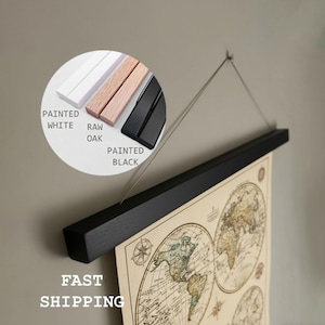 Peut inclure: Un support de carte en bois noir avec une impression de carte du monde. Le support est suspendu par un fil fin. Un encart circulaire montre les options : blanc peint, chêne brut et noir peint. Le texte "FAST SHIPPING" est en bas.