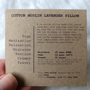 May include: A brown cotton muslin lavender pillow with the text "Cotton Muslin Lavender Pillow" printed on the front. The pillow is filled with lavender, rice, and flax seed. The text on the back of the pillow lists uses for the pillow, including yoga, meditation, relaxation, migraine, tension, cramps, and travel. The text also lists heating and cooling instructions for the pillow, including microwave, oven, and freezer times.
