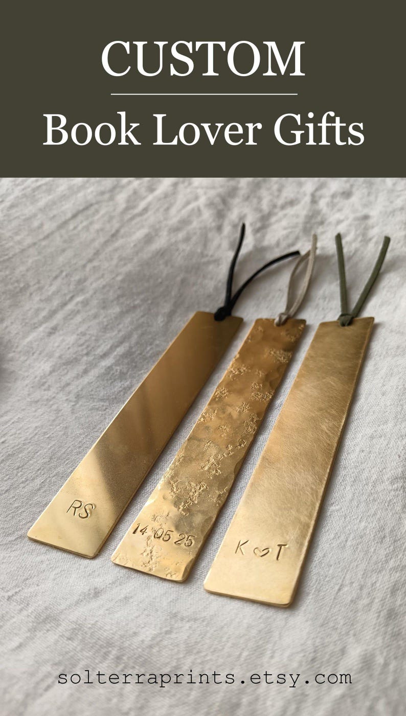 Peut inclure: Trois marque-pages rectangulaires en laiton avec des cordons en cuir. Le premier est lisse avec les lettres RS, le deuxi&egrave;me a une texture martel&eacute;e avec la date 14 05 25, et le troisi&egrave;me a une finition bross&eacute;e avec les lettres K et T et un c&oelig;ur.