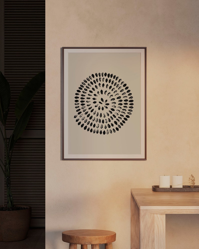 May include: A framed print with a black and white abstract design of a circle with a pattern of small ovals. The print is on a beige background and is framed in a brown frame.