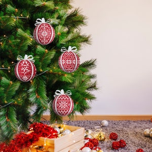 May include: A Christmas tree decorated with red and white patterned baubles. The tree is next to a wooden crate filled with more baubles and red and silver tinsel.