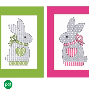 May include: Two cross-stitch patterns for Easter bunnies. The bunny on the left is in a green frame and has a green and white heart. The bunny on the right is in a pink frame and has a pink and white striped heart.