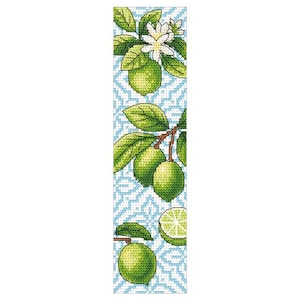 Puede incluir: Un punto de cruz con un diseño de árbol de lima. El marcapáginas tiene un fondo azul claro con un patrón geométrico blanco. Se representan limas verdes, hojas y flores blancas. También se muestra una rodaja de lima.