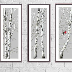 May include: Three framed art prints depicting birch trees against a grey backdrop. The prints are minimalist, with the trees in white and grey tones. One print shows a red bird perched on a branch, adding a splash of colour.