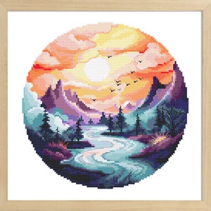 Puede incluir: Un patrón circular de punto de cruz que representa un paisaje de montaña al atardecer. La escena presenta un río serpenteando a través de un bosque, con montañas en el fondo y un cielo naranja brillante con nubes y pájaros volando por encima.