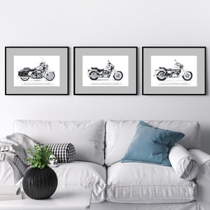 May include: Three black framed prints of motorcycle drawings. Each print features a different motorcycle design. The prints are hung on a white wall above a white couch.