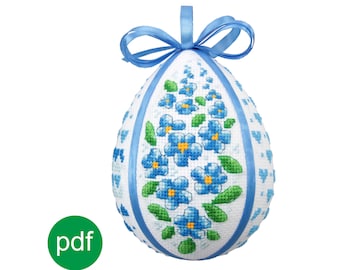 Può includere: Un uovo di Pasqua bianco con un nastro blu e un disegno di fiori blu nontiscordardime.