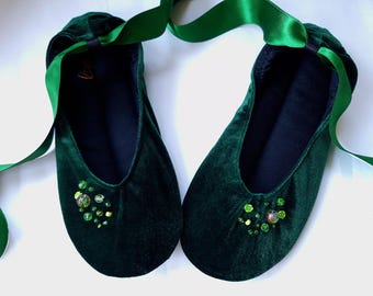 May include: A pair of dark green velvet ballet slippers with green gem embellishments and matching green satin ribbon ties.