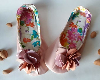 May include: A pair of pink satin slippers with a floral print lining and a large pink flower embellishment on the toe.
