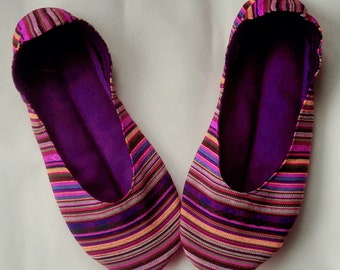 May include: A pair of purple and pink striped fabric slippers. The slippers have a purple lining and are made of a soft, comfortable material.