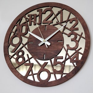 May include: A brown wooden clock with a mirrored face and black numbers. The numbers are cut out of the wood and the mirror is visible behind them. The clock hands are silver.