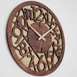 May include: A brown wooden wall clock with a mirrored face. The clock face has a geometric design with the numbers 1 through 12 cut out. The clock hands are silver.