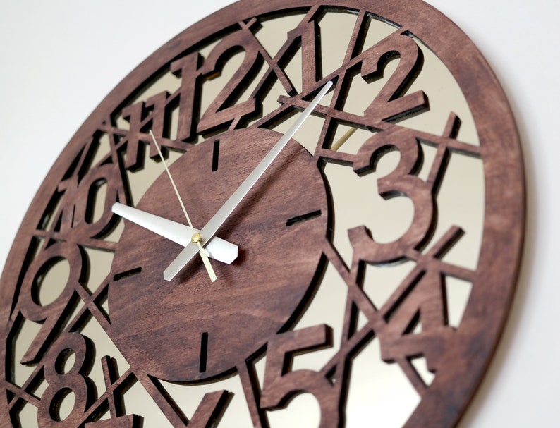 May include: A brown wooden clock with a mirrored face. The numbers 1 through 12 are cut out of the wood and the clock hands are silver.