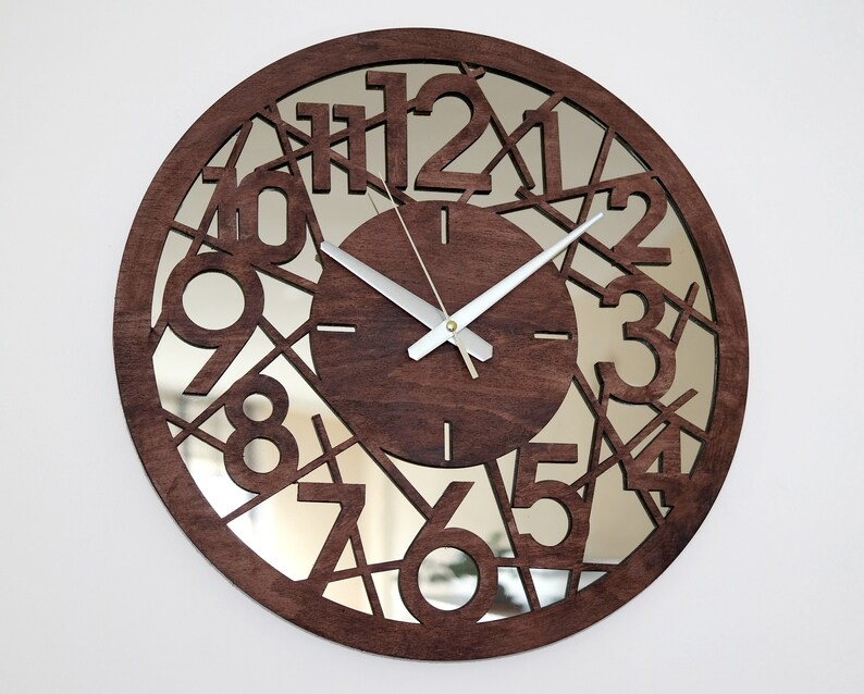 May include: A brown wooden clock with a mirrored face. The numbers 1 through 12 are cut out of the wood and the mirror is visible behind them. The clock hands are silver.