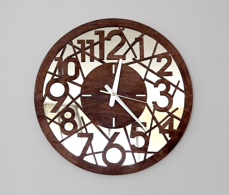 May include: A brown wooden clock with a mirrored face. The numbers 1 through 12 are cut out of the wood and the clock hands are white.