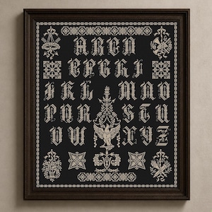 May include: A framed cross-stitch sampler featuring a black background with cream-colored embroidery. The design displays the alphabet in an ornate gothic font, centered around a detailed eagle motif, surrounded by intricate floral and geometric borders.