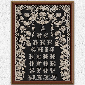 May include: Black and white cross stitch pattern of the alphabet with floral accents. The pattern is framed in a brown frame. The text "Handmade with love" and "Selenmar Xstitch" is visible in the image.
