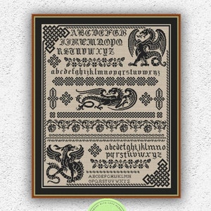 Könnte beinhalten: Ein schwarzes und weißes Kreuzstichmuster mit einem Drachen und einer Vielzahl von Buchstaben und Bordüren. Das Muster ist in einem schwarzen Rahmen mit goldener Umrandung gerahmt.
