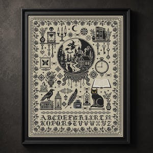 May include: A framed cross-stitch sampler featuring a black and beige design with a central crystal ball containing a witch, a cat, and a house. The border includes roses, and the bottom displays the alphabet in a gothic font, surrounded by various occult and mystical icons like skulls, books, and candles.