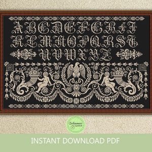 Puede incluir: Un muestrario de punto de cruz enmarcado con fondo negro y letras y diseños color crema. El diseño presenta el alfabeto en una fuente ornamentada, motivos florales y de querubines, y un emblema de águila. El texto "INSTANT DOWNLOAD PDF" está en la parte inferior.