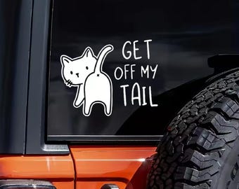 May include: A white vinyl decal applied to a dark vehicle window featuring a line drawing of a cat facing away with its tail raised. The text GET OFF MY TAIL is printed in a simple, hand-drawn style font to the right of the cat illustration.